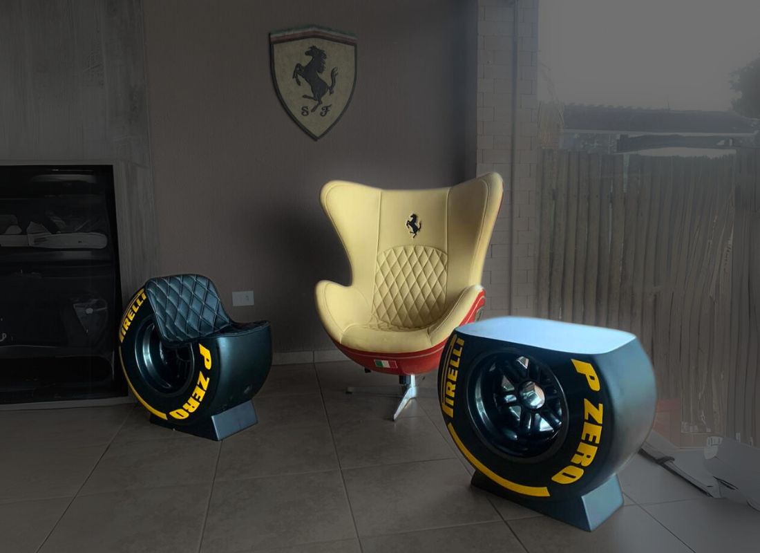 Sala com poltrona Ferrari bege com base vermelha, puff e mesa de centro em formato de pneu de competição preto com letras amarelas