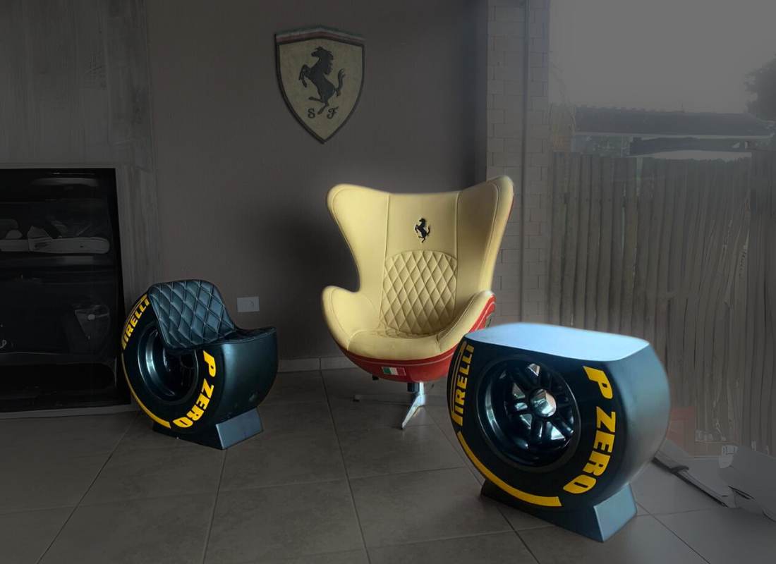 Sala com poltrona Ferrari bege com base vermelha, puff e mesa de centro em formato de pneu de competição preto com letras amarelas